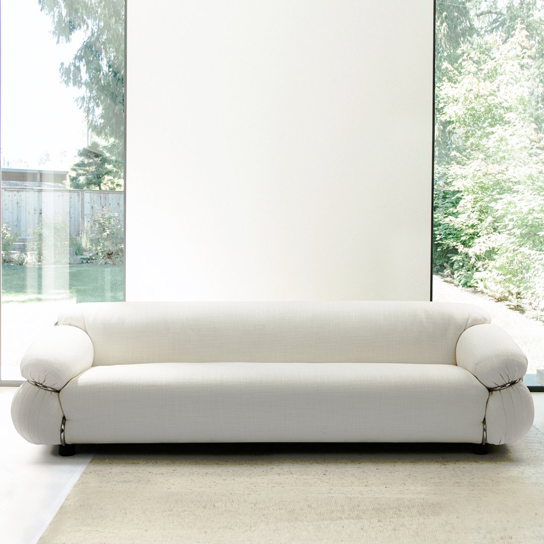Cream-colored sofa with rounded arms in front of large windows
